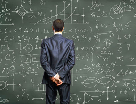 Man in suit stands staring at knowledge board
